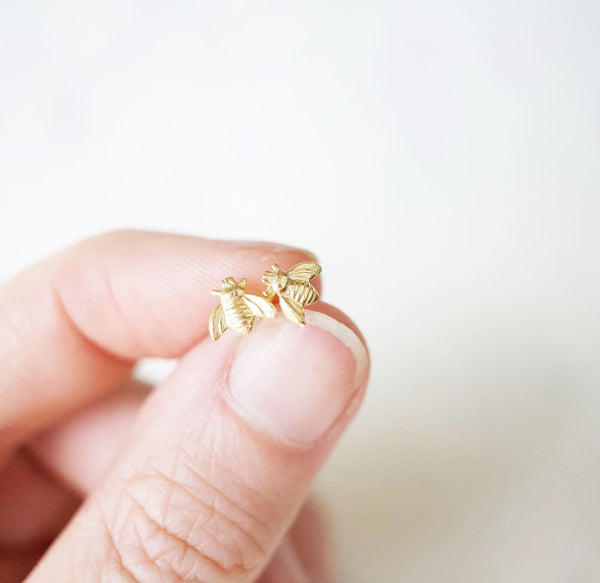 hand holding petite gold bumble bee post earrings