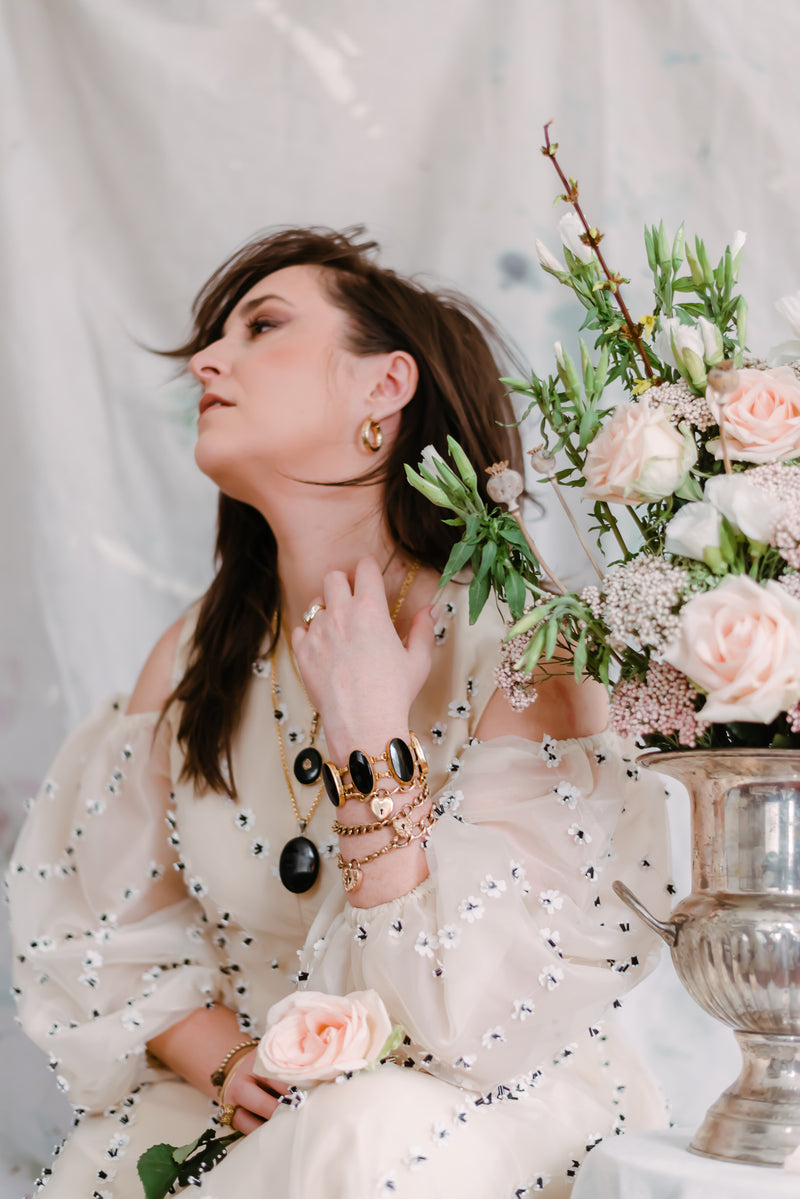 women wearing lots of jewelry next to a bouquet of flowers