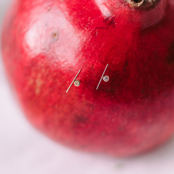 two gold and diamond post earrings in the side of a pomegranate 
