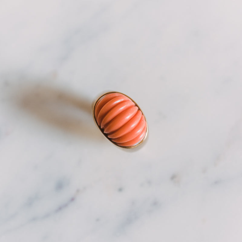gold dome ring with a carved piece of coral in the center