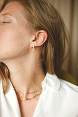 woman wearing gold an diamond huggie earrings